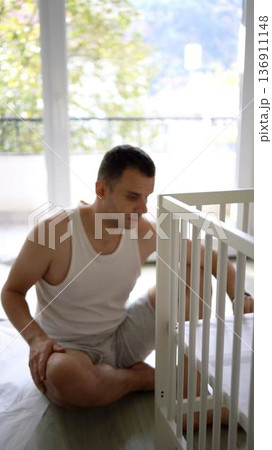 Future father assembling a white crib in a minimalist nursery ro 136911148