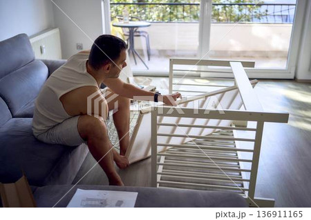 New dad to be building a cradle for his newborn in a bright simple room 136911165