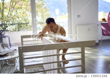 New dad to be building a cradle for his newborn in a bright simple room New dad to be building a cradle for his newborn in a bright simple room 136911168