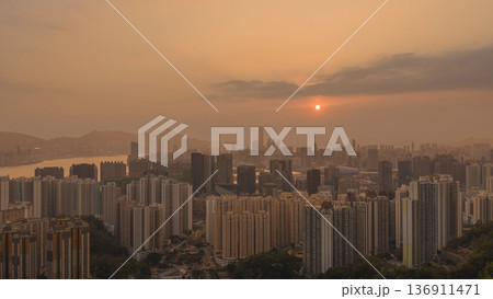 Hazy Kowloon skyline glowing under warm sunset Feb 19 2026 136911471