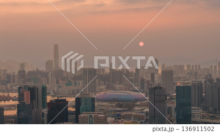 Hazy Kowloon skyline glowing under warm sunset Feb 19 2026 136911502
