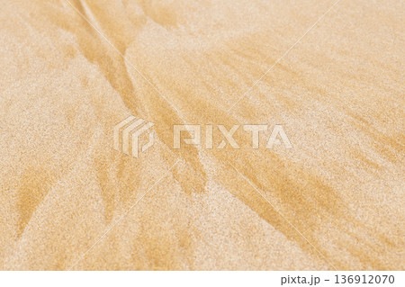 Wind patterns on golden sand surface creating textured background in natural environment 136912070