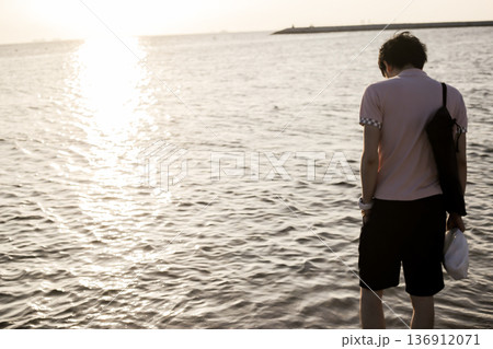 夕暮れの浜辺を歩く男性 136912071