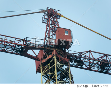 Industrial construction crane against a clear blue sky. Heavy machinery for building and development project. Lifting equipment. 136912666