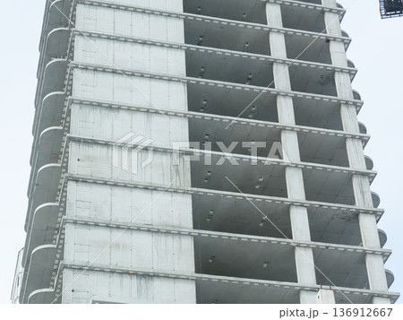 Concrete structure of a modern skyscraper under construction against a clear sky, showing progress on an urban development project. 136912667