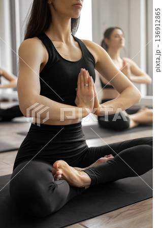 A group of women practice yoga in a bright studio, focusing on their breath and inner peace during a guided meditation session A group of women practice yoga in a bright studio, focusing on their breath and inner peace during a guided meditation session 136912865