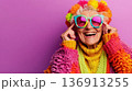 Cheerful elderly woman wears colorful clothing and oversized sunglasses while posing against a vibrant purple backdrop 136913255
