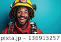 Smiling firefighter poses confidently in bright uniform against vibrant blue background while showcasing dedication to safety and community service 136913257