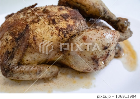 Whole roasted chicken with crispy skin resting on a white plate, prepared delicious poultry meal for dinner or Thanksgiving. Whole roasted chicken with crispy skin resting on a white plate, prepared delicious poultry meal for dinner or Thanksgiving. 136913984