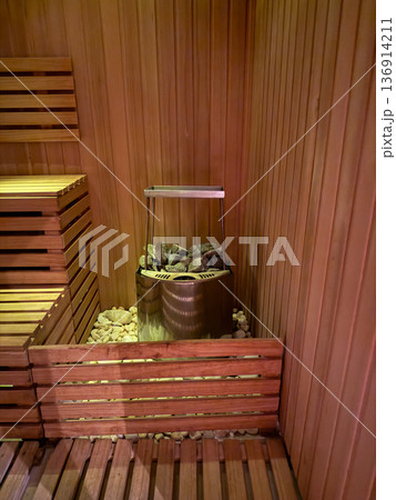 Wooden sauna interior with heater and hot stones in corner. Wellness ritual, heat therapy, relaxation practice, and spa lifestyle concept 136914211