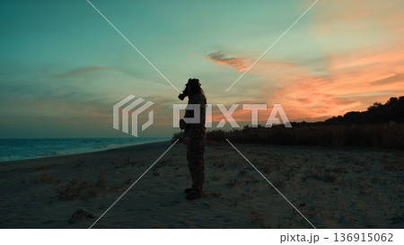 Soldier in silhouette at sunset on a beach contaminated by a nuclear attack 136915062