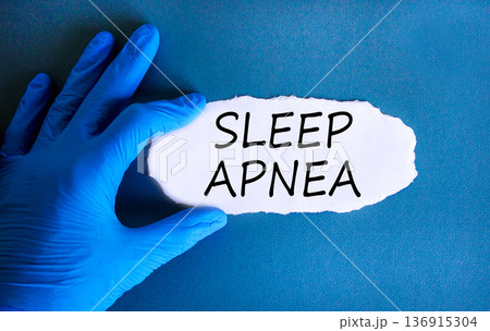 Sleep apnea symbol. Concept words Sleep apnea on beautiful white paper. Doctor's hand in blue medical glove. Beautiful blue background. Medical healthy lifestyle sleep apnea concept. 136915304