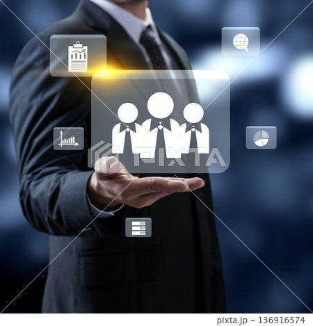 Professional businessman presenting a team icon for human resources and workforce management, surrounded by various business data and analytics symbols 136916574