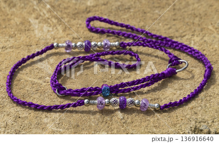 A vibrant purple handmade dog show lead displayed on a stone surface. The lead features intricate braiding and is adorned with purple, blue, and silver beads for professional exhibition use 136916640