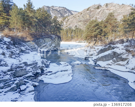 Scenic river flowing through snowy canyon with evergreen trees on mountains. Beautiful winter landscape for travel and nature magazine. Scenic river flowing through snowy canyon with evergreen trees on mountains. Beautiful winter landscape for travel and nature magazine. 136917208