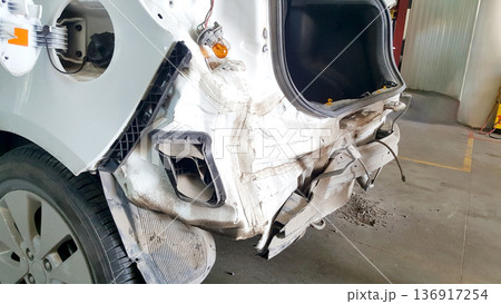 White car with rear bumper removed at an auto body shop, showing collision damage. Vehicle repair and service concept for accident. White car with rear bumper removed at an auto body shop, showing collision damage. Vehicle repair and service concept for accident. 136917254
