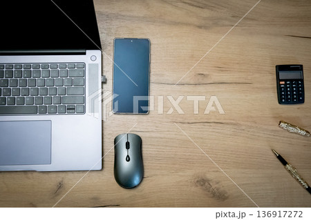 Laptop keyboard with mouse, phone, calculator, and pen on a wood desk for business, education, work from home, office workspace concept. Laptop keyboard with mouse, phone, calculator, and pen on a wood desk for business, education, work from home, office workspace concept. 136917272