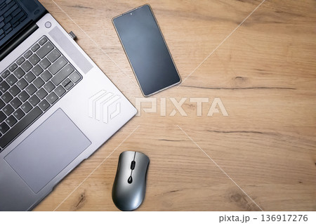 Laptop, phone, and mouse on a wooden desk. Digital devices for work, study, and communication. Flat lay top view. Laptop, phone, and mouse on a wooden desk. Digital devices for work, study, and communication. Flat lay top view. 136917276