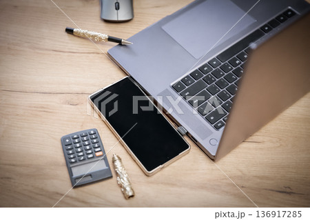 Laptop, phone and calculator on wooden desk for business work. Concept of modern workplace and digital technology for finance and accounting. 136917285