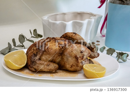 Roasted whole chicken with lemon on a white plate. Delicious homemade meal for dinner. Culinary food photography for restaurant menu. 136917300