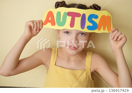 A child holds the inscription autism. A disease with impaired mental development, a lack of social interaction, problems in communication and behavior. Nervous system disease A child holds the inscription autism. A disease with impaired mental development, a lack of social interaction, problems in communication and behavior. Nervous system disease 136917429