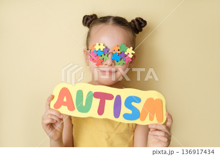 Child with Autism lettering against puzzle symbol background. Clinical context of autism spectrum disorder, neurodevelopmental condition, behavioral evaluation, sensory processing differences 136917434