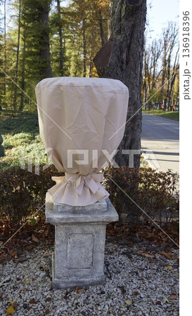 A flower pot in a city park is covered with a textile cover for the winter A flower pot in a city park is covered with a textile cover for the winter 136918396
