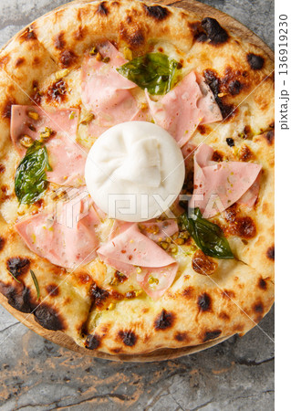 Close-up of neapolitan pizza with whole burrata cheese, mortadella and crushed pistachios. Vertical top view Close-up of neapolitan pizza with whole burrata cheese, mortadella and crushed pistachios. Vertical top view 136919230