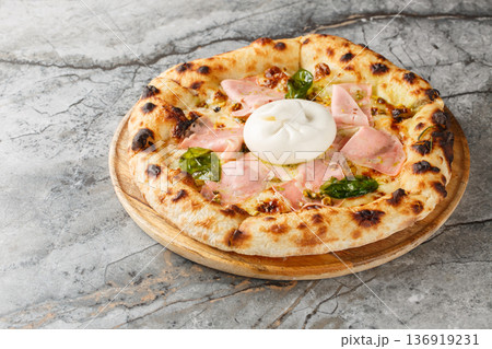 Charred crispy mortadella and burrata pizza with basil and pistachios close-up on a wooden board. Horizontal 136919231