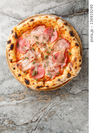 Close-up of neapolitan pizza with prosciutto, salami, tomato sauce and mozzarella on wooden board. Garnished with fresh thyme. Marble background top view Close-up of neapolitan pizza with prosciutto, salami, tomato sauce and mozzarella on wooden board. Garnished with fresh thyme. Marble background top view 136919240