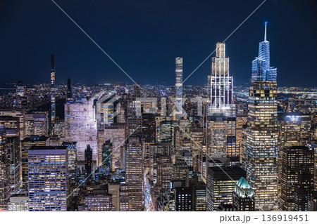 Night aerial view of Midtown Manhattan skyline with modern illuminated skyscrapers and dense city lights in New York City USA Night aerial view of Midtown Manhattan skyline with modern illuminated skyscrapers and dense city lights in New York City USA 136919451