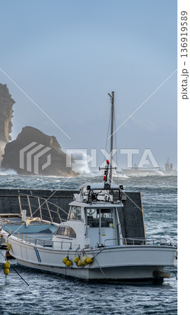 中木漁港に停泊している漁船と岩場見打ち寄せる荒波 136919589