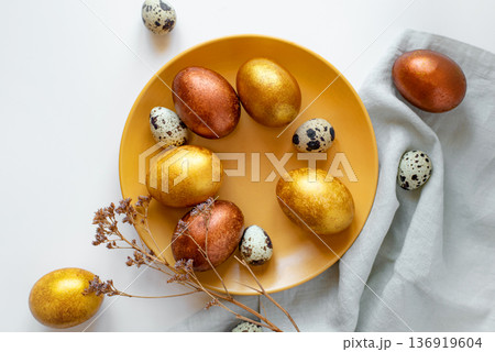 Golden and bronze Easter eggs in a orange plate 136919604