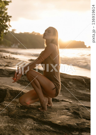 Beautiful young woman posing on rocky beach at sunset, sunshine portrait 136919614