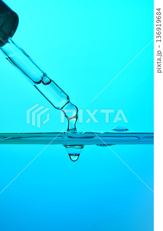 Pipette dropping blue liquid into clear water Pipette dropping blue liquid into clear water 136919684