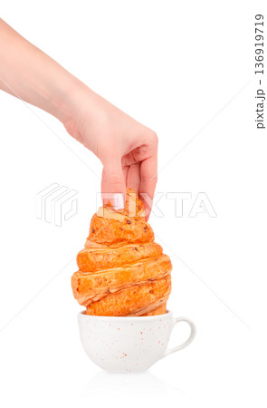 Croissant in coffee cup held by female hand Croissant in coffee cup held by female hand 136919719