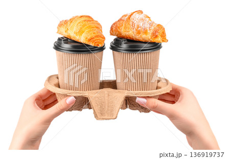 Two takeaway coffee cups with croissants in hands isolated on white background Two takeaway coffee cups with croissants in hands isolated on white background 136919737