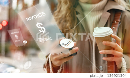 Person using a phone to make a banking invoice payment while holding a coffee cup 136921304