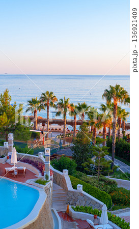 Relaxing scene by the beach with palm trees and a swimming pool in the evening 136921409