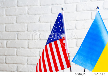 Flags of the United States and Ukraine displayed on a white brick wall during a cultural event 136921413
