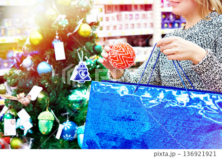Woman puts red Christmas ball onblue bag Woman puts red Christmas ball onblue bag 136921921
