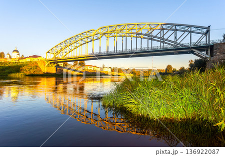 View on the steel arch bridge across the Msta river in summer in sunset light. Built in 1905. Borovichi, Russia 136922087