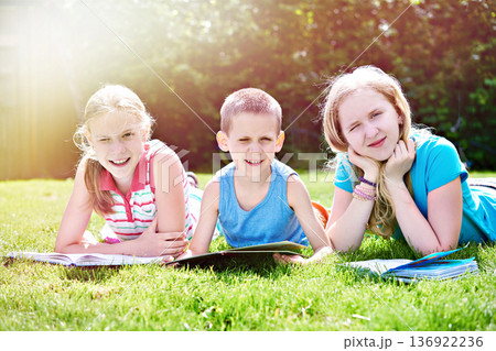 Children reading book on grass Children reading book on grass 136922236