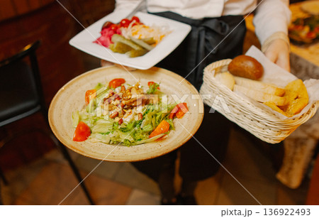 Salads and other dishes in the hands of the waiter 136922493
