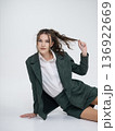 An elegant white woman in business suit talks on a red telephone while sitting on a chair against the backdrop of an isolated space. Office. Curly hair, brown-haired 136922669