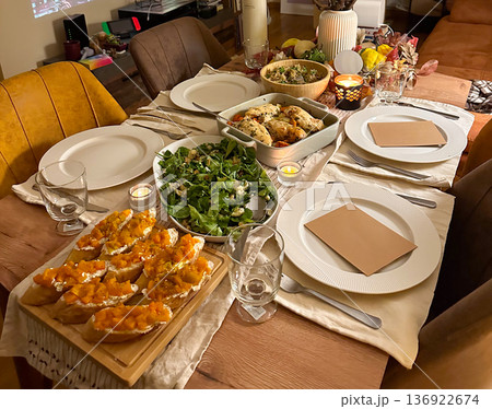 Home festive dinner table with salad chicken and bruschetta. Cozy gathering, autumn evening, family hospitality and comfort food concept 136922674