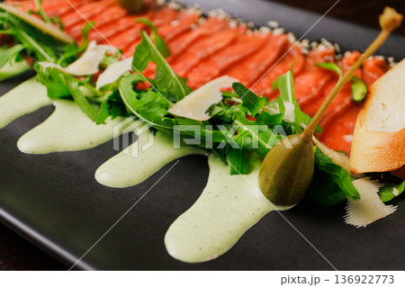 A plate with sliced red fish, bread and greens A plate with sliced red fish, bread and greens 136922773