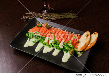 A plate with sliced red fish, bread and greens A plate with sliced red fish, bread and greens 136922777