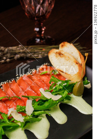 A plate with sliced red fish, bread and greens A plate with sliced red fish, bread and greens 136922778