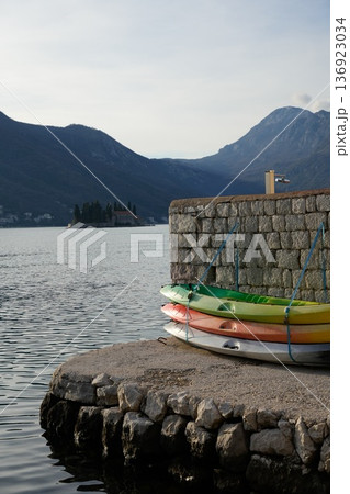 Colorful Kayaks Stacked on Dock with Mountains Colorful Kayaks Stacked on Dock with Mountains 136923034